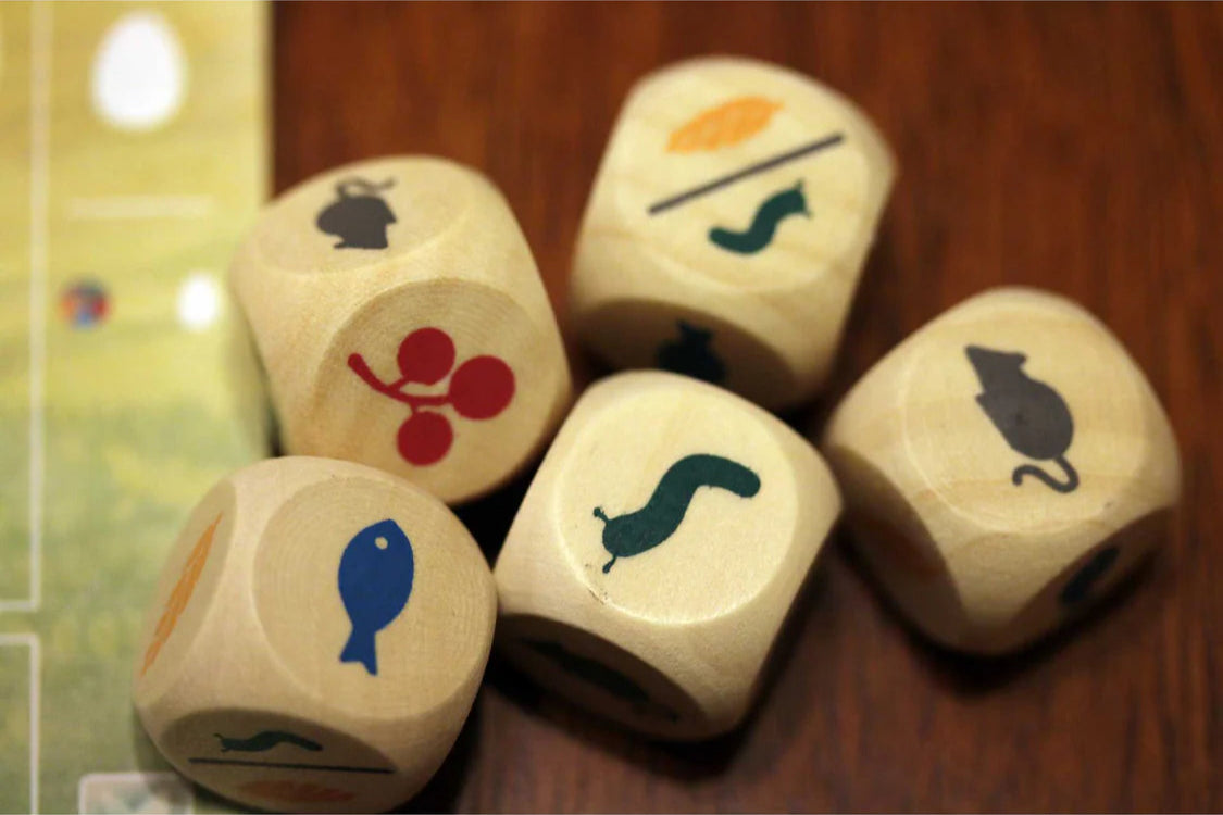Wooden dice with animal and object symbols on a wooden surface